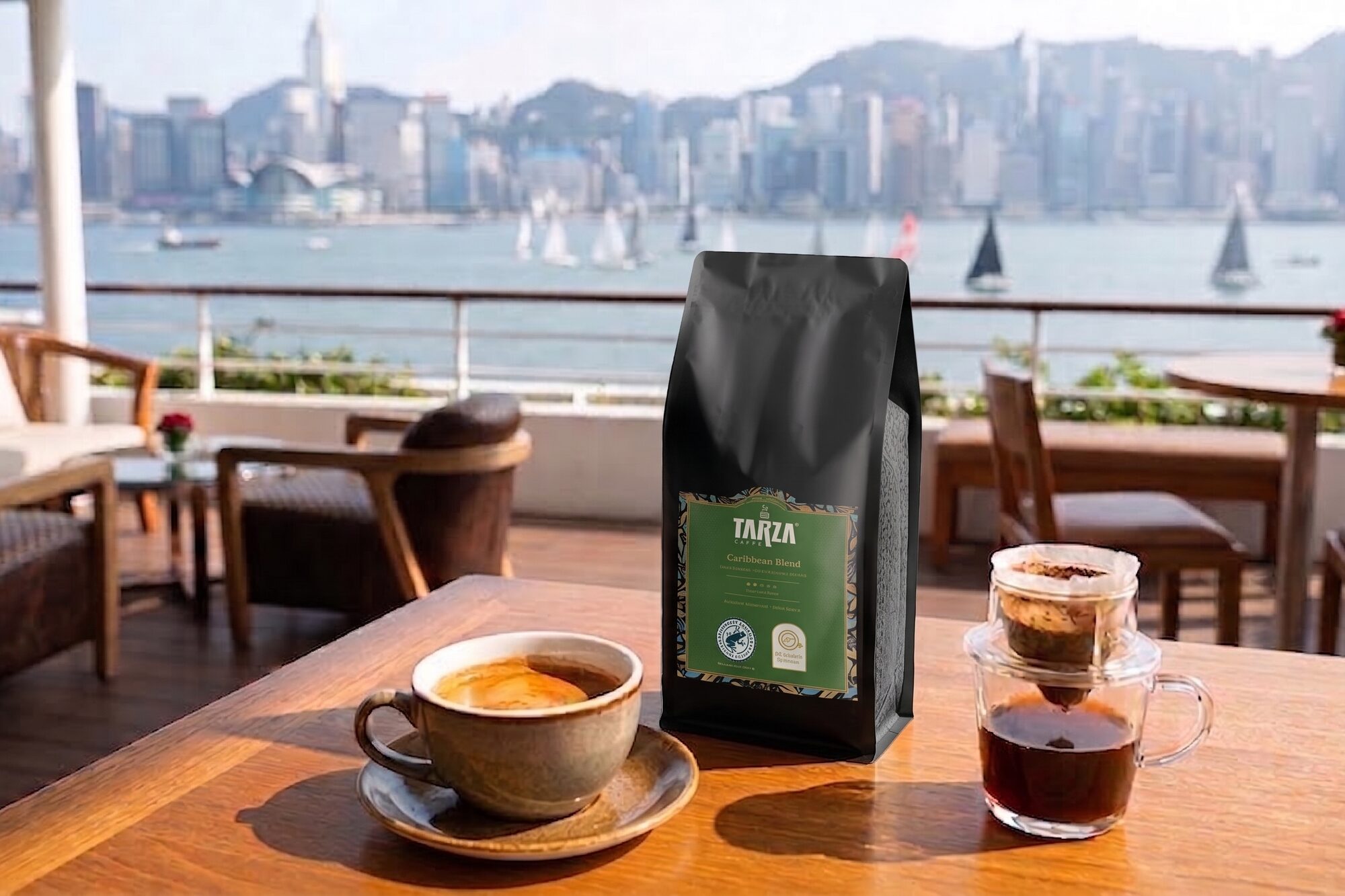 A bag of TARZA Caffe coffee on a table on a Hong Kong waterfront terrace, two cups of coffee beside it, Victoria Harbour and racing sailboats behind