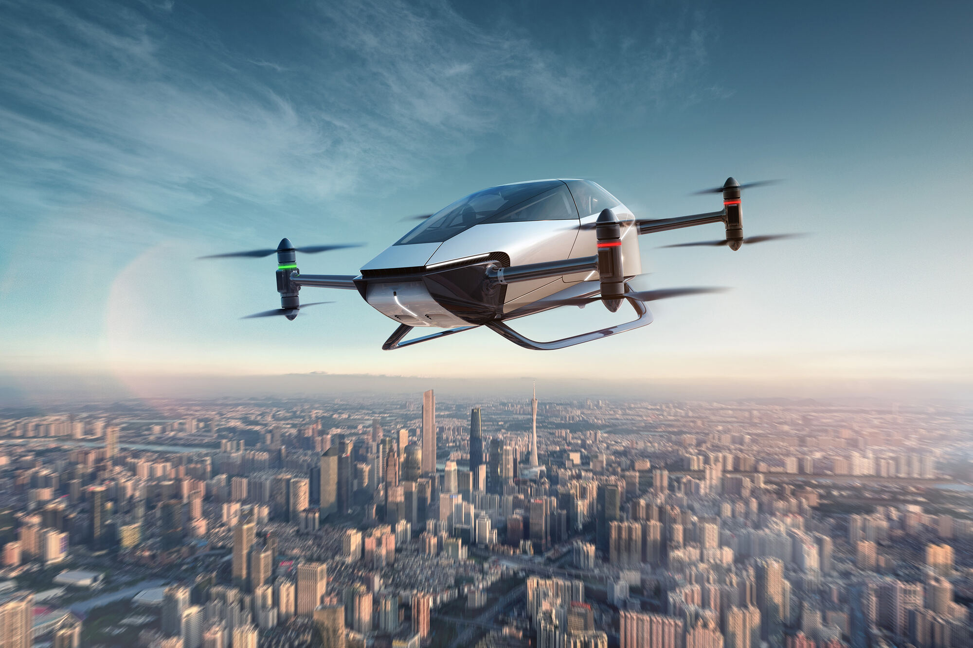 The XPENG X2 flying vehicle in the air above a city skyline at dusk, its four rotors turning